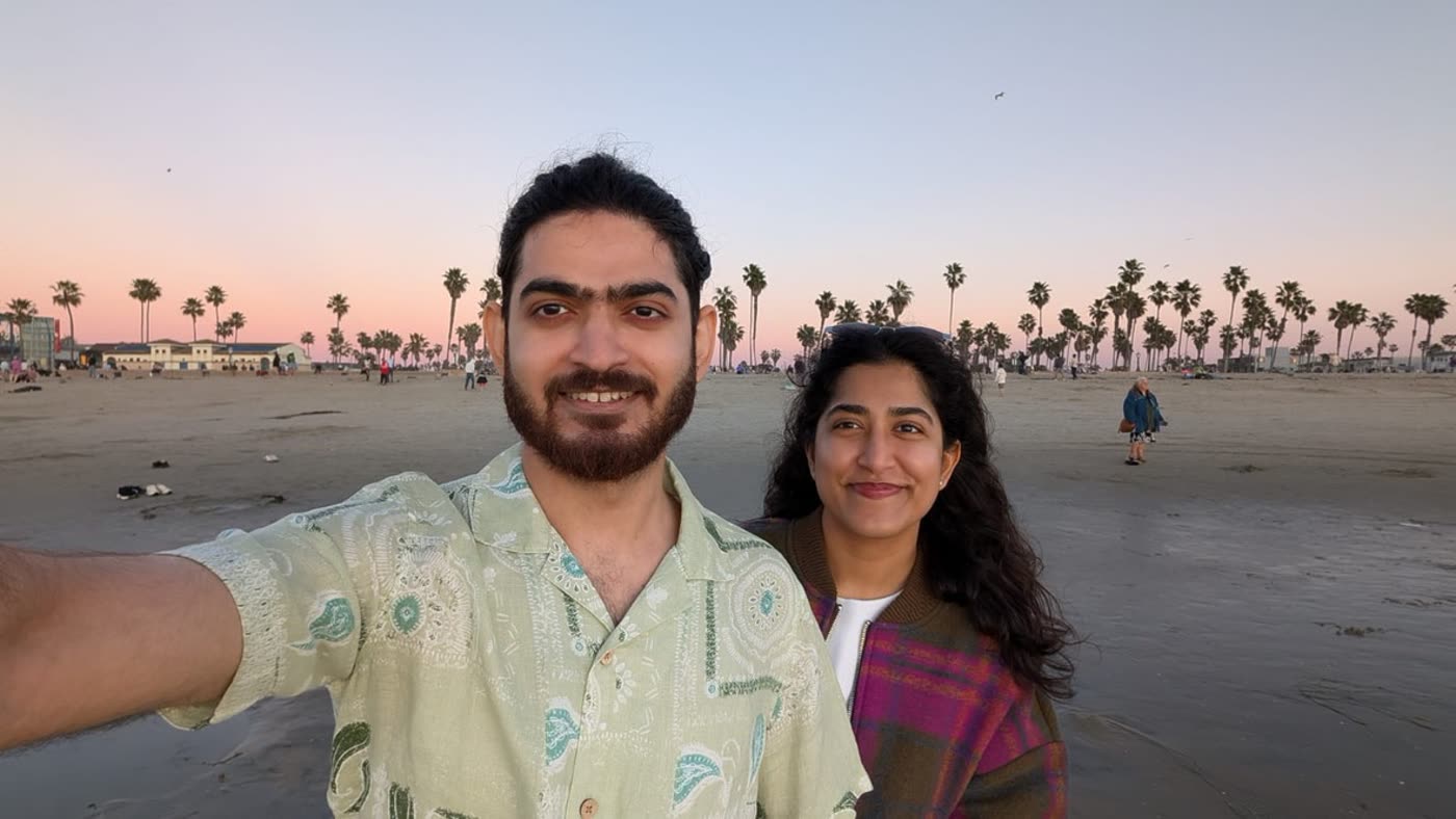 Abirami and Prateek on a palm-lined beach at dusk