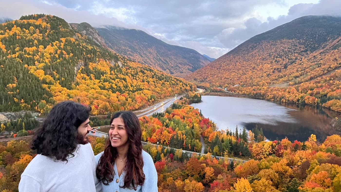 Abirami and Prateek above a valley of autumn colour